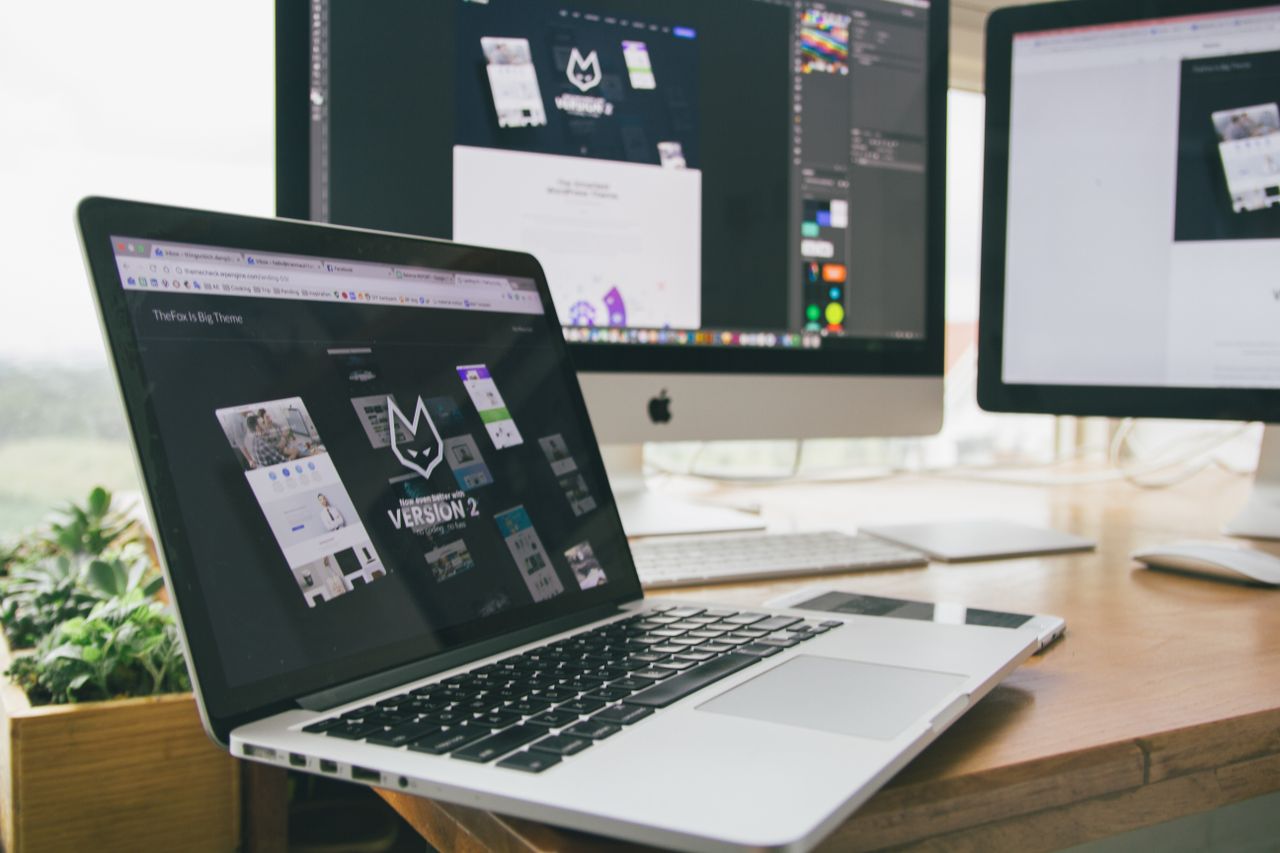 Un espace de travail élégant avec un ordinateur portable et des écrans montrant un logiciel de design.